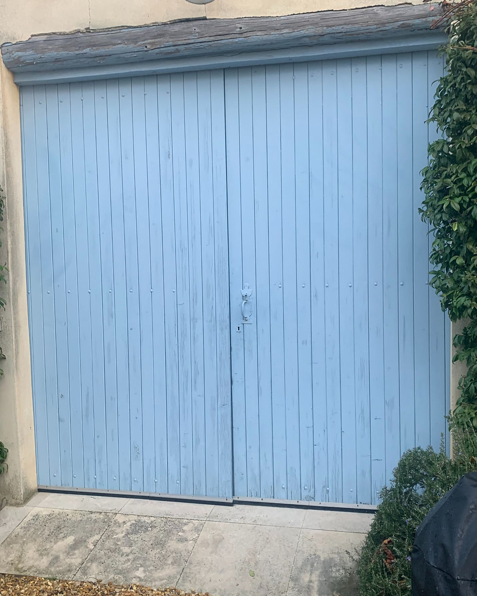 Garagentor 2 flüglich in blassblauer Farbe an Betonmauer Farbe