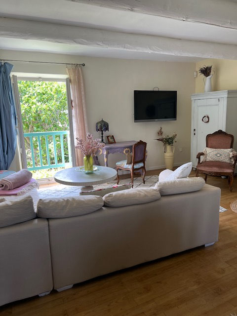 Helles Wohnzimmer mit Vintage-Möbeln, Balkonblick, gemütlichem Sofa und stilvoller Dekoration