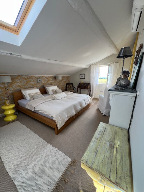 Helles Schlafzimmer mit Doppelbett, Dachschräge, Fensterblick ins Grüne und gemütliche Einrichtung