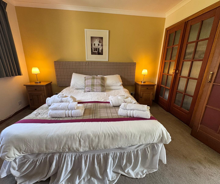 Double bedroom in a 3 bedroom villa at Kilconquhar Castle Estate with bedside tables and soft lighting.