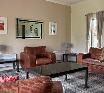Spacious lounge with leather sofas in a self-catering villa at Kilconquhar Castle Estate.