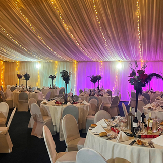 Decorated marquee with warm fairy lights, coloured uplighting and set dining tables for a Christmas party night at Kilconquhar Castle Estate in Fife