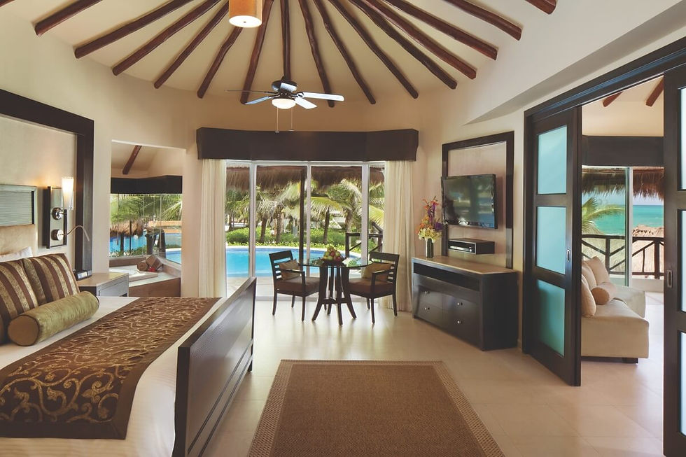 Interior of a luxury suite at Karisma Resorts, featuring a spacious bedroom, sitting area, and view of the pool and ocean.