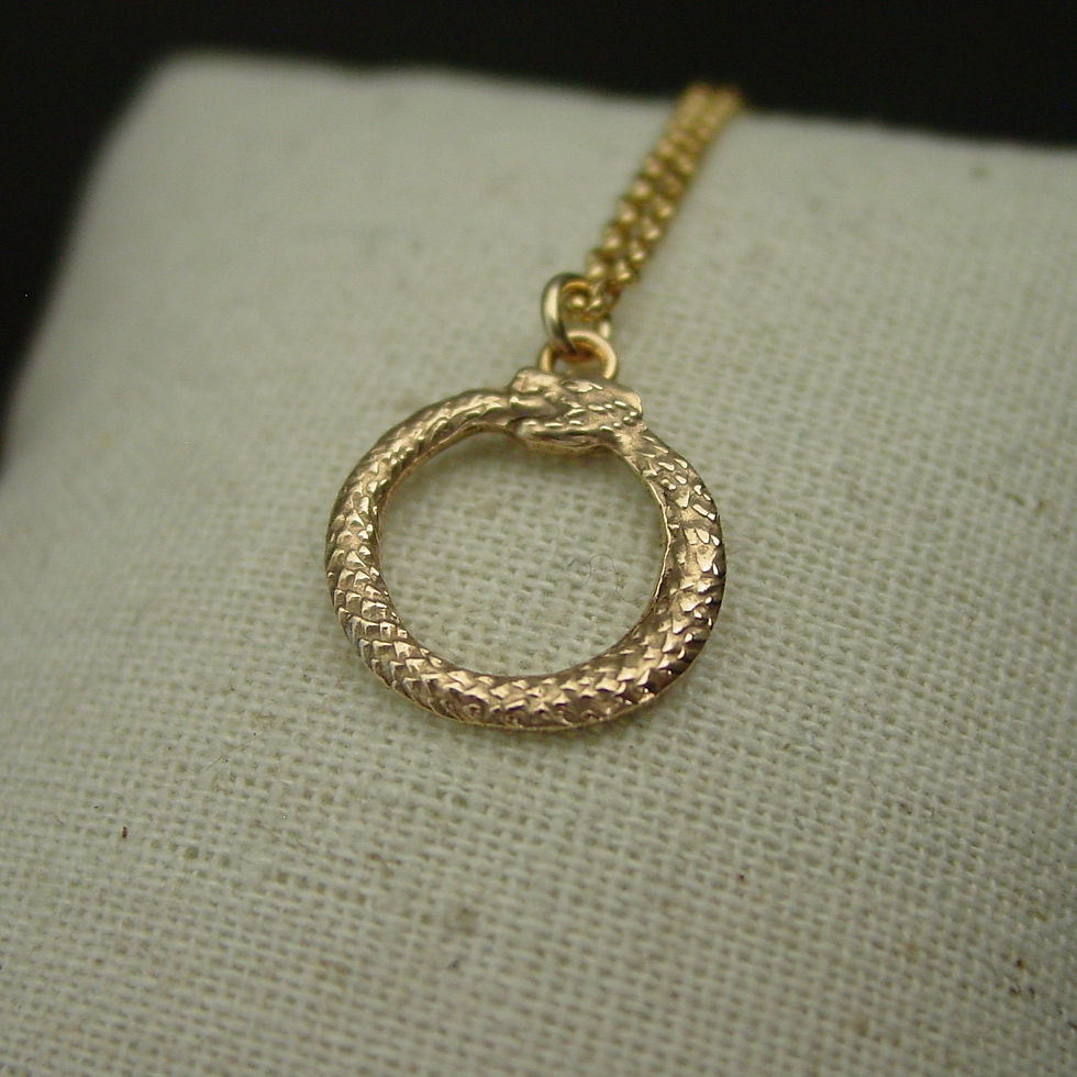 Tiny Ouroboros necklace on pillow close up
