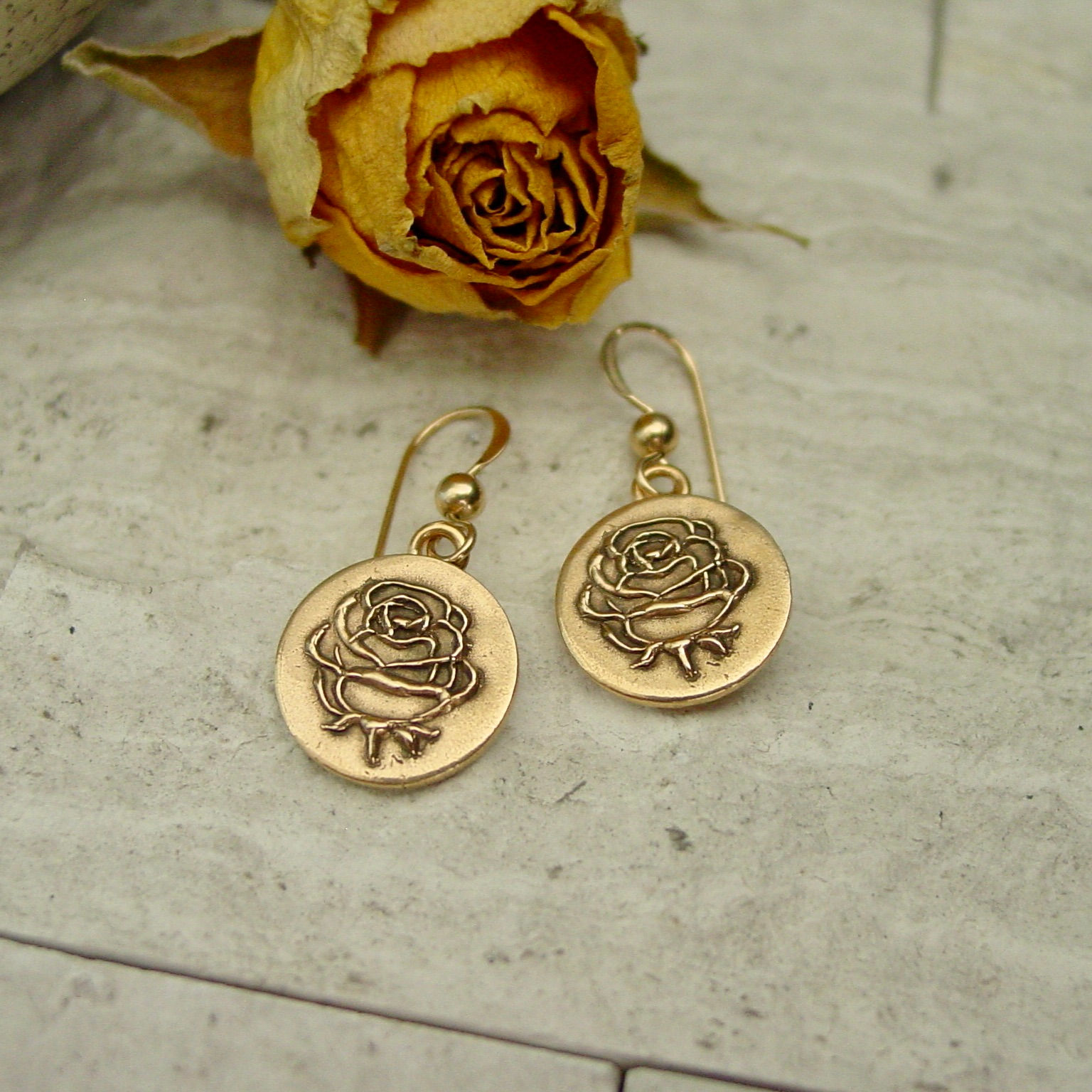 Gold rose earrings next to yellow rose
