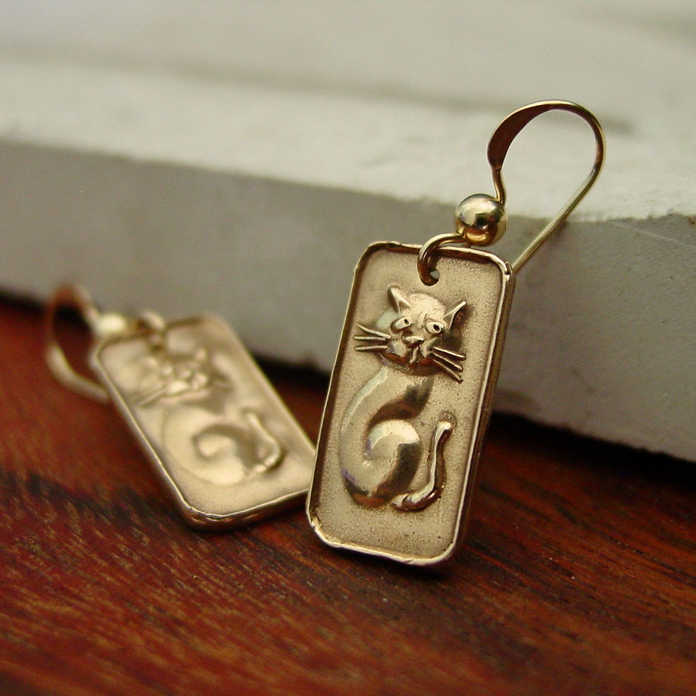 Tiny cat earrings on marble