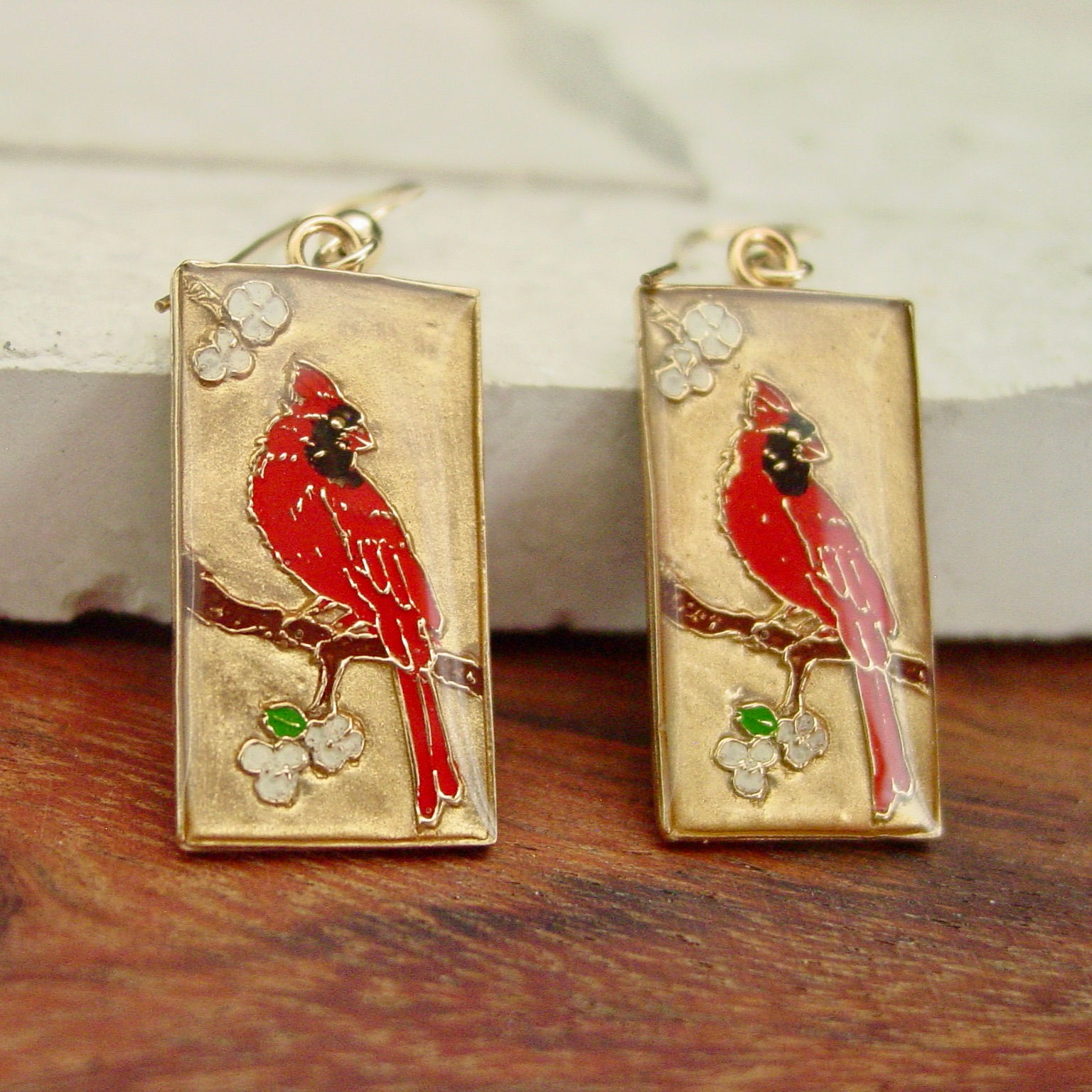 Small red cardinal earrings on marble