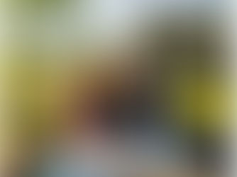 Smiling couple at a picnic table with a map, smartphone, and coffee, near an RV in a scenic countryside setting. Bright and cheerful mood.