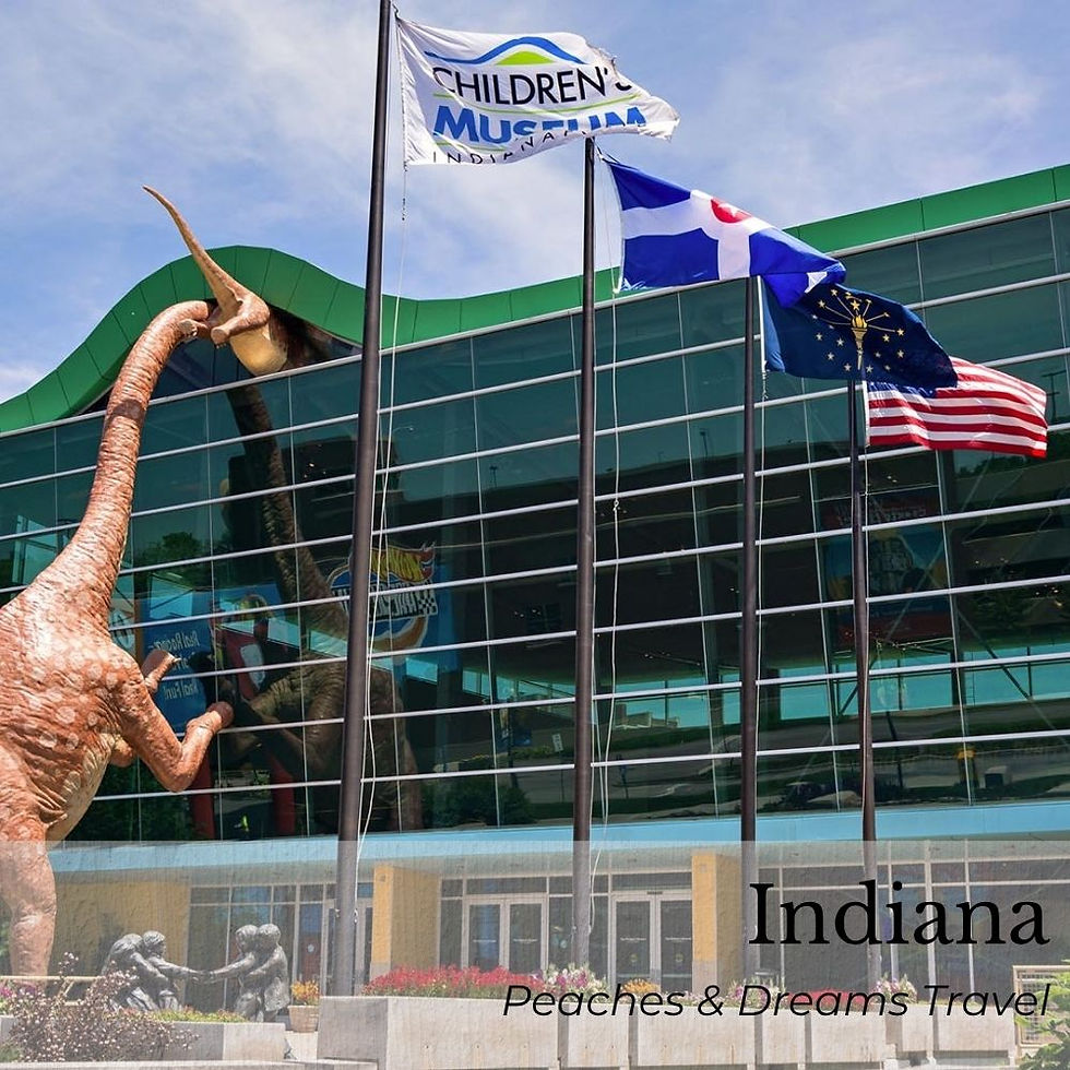 Dinosaur sculpture at entrance of Children's Museum in Indiana, with flags waving. Glass facade reflects clear sky. Text: Peaches & Dreams Travel.