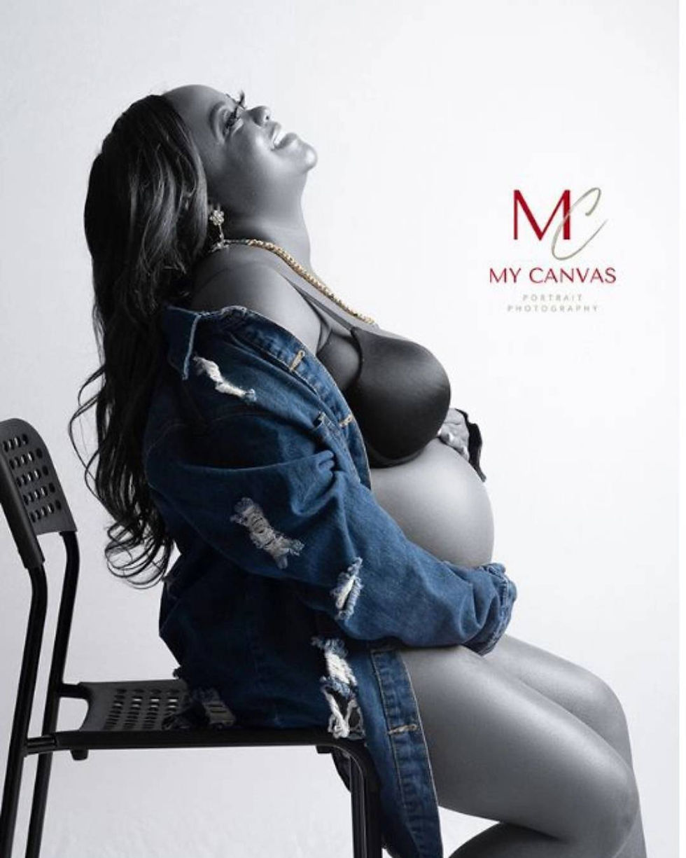 Black and white maternity photo in Killeen, TX of expecting mom in fitted black outfit with hands on baby bump.