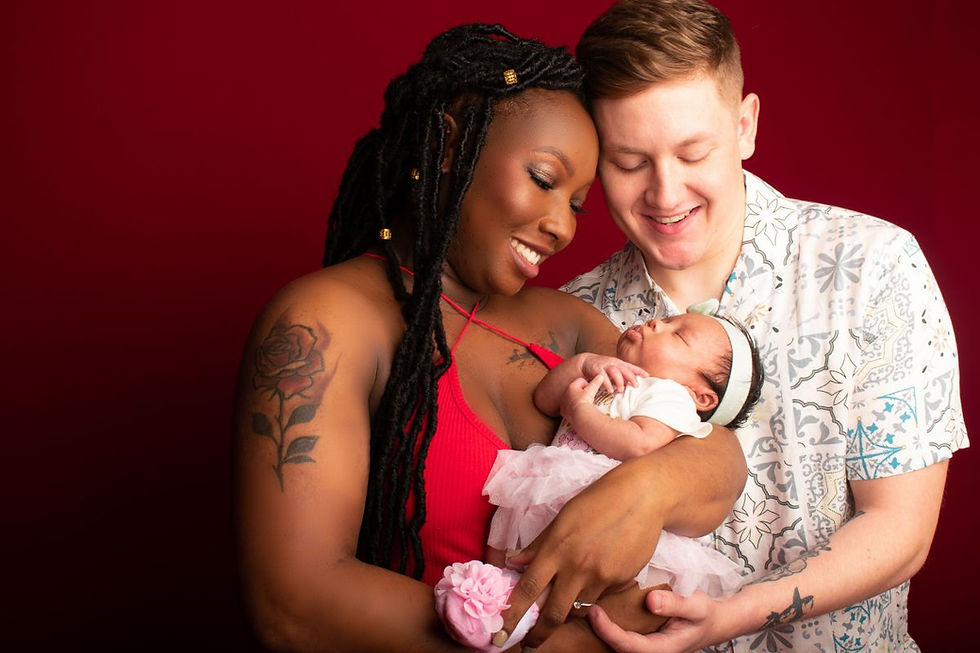 Parents looking down at their newborn baby while holding her together during a family portrait