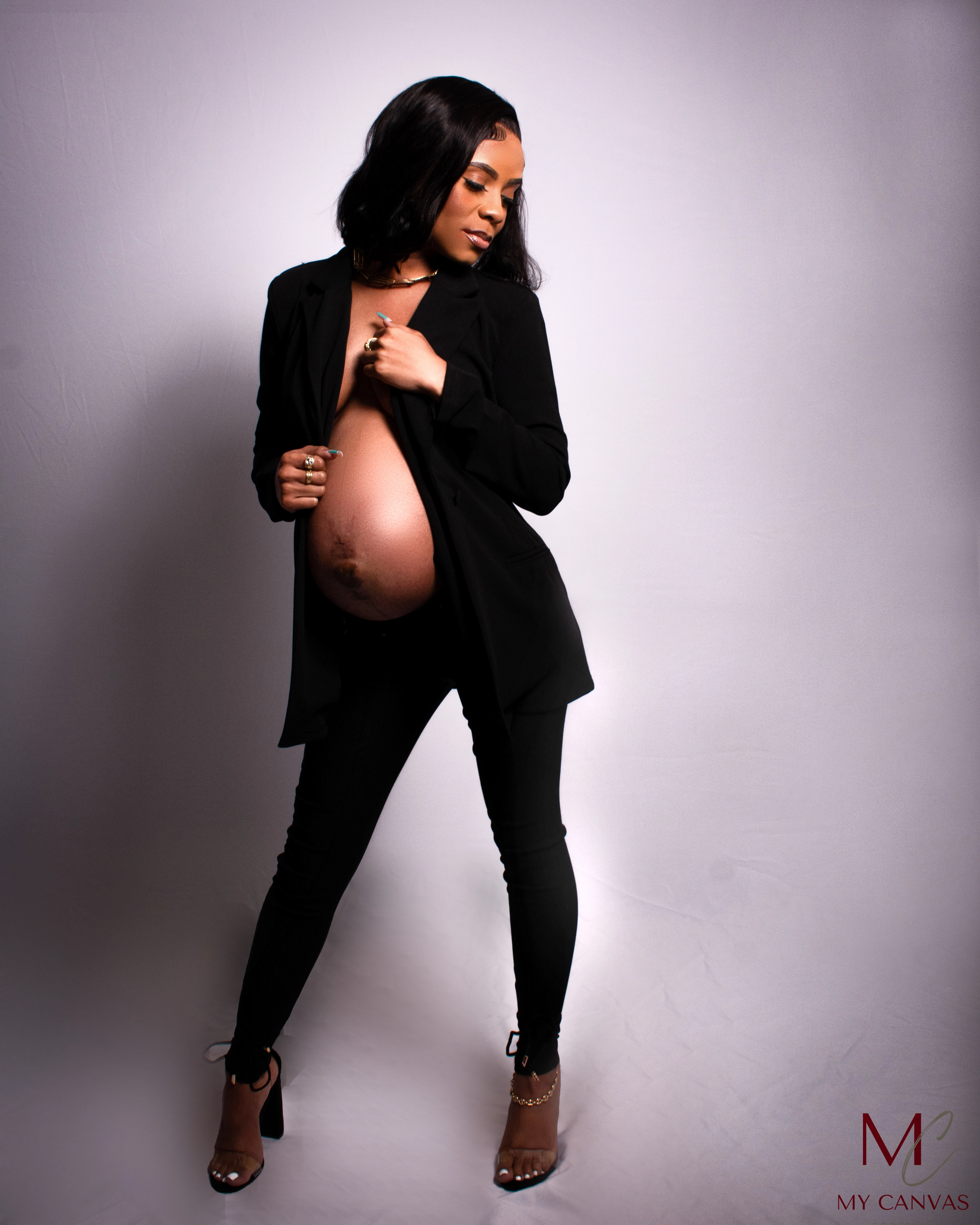 A Killeen mother-to-be poses with sophistication in a black blazer, the jacket artfully open to reveal her pregnant form, exuding confidence and the intimate connection to her unborn child.