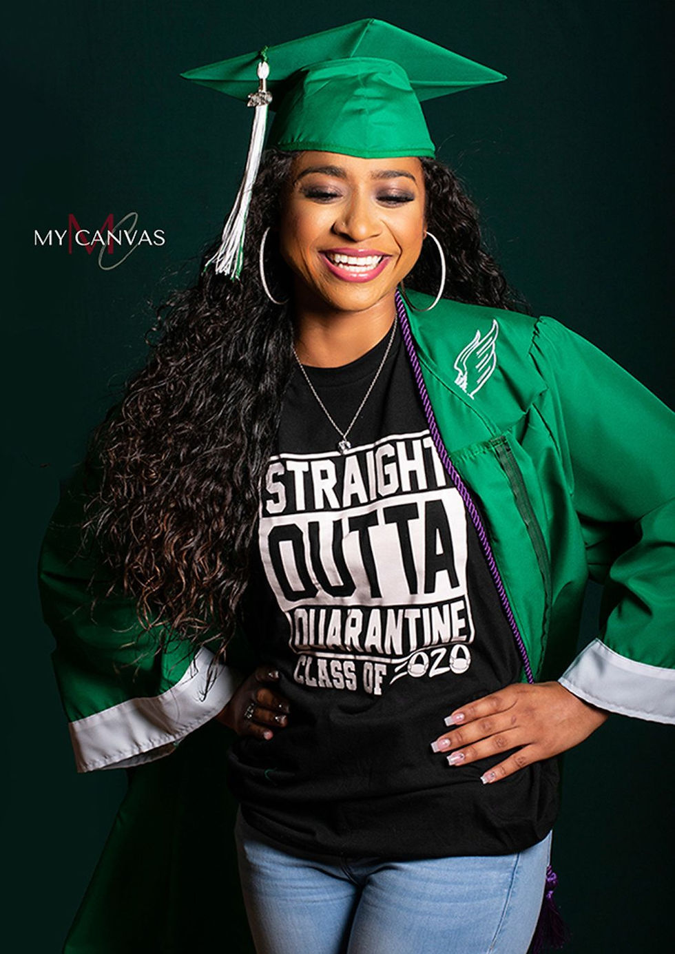 Graduate wearing a green cap and gown over a Class of 2020 graphic shirt and jeans.