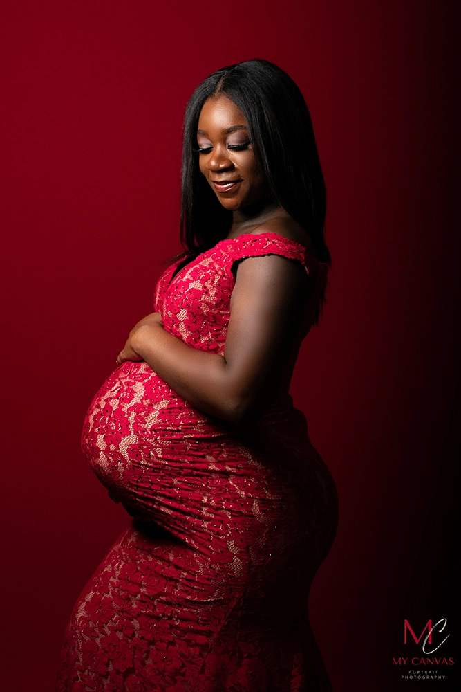 In a stylish red lace maternity dress, a mother-to-be in Killeen, Texas, strikes a sassy pose, radiating confidence and the beauty of pregnancy.
