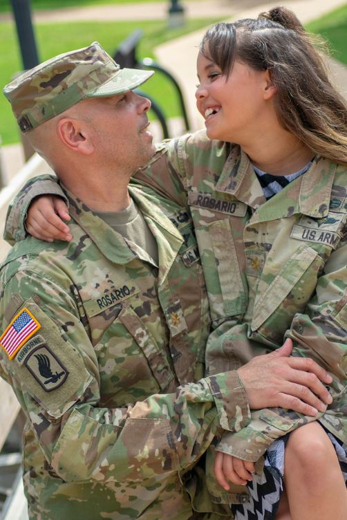 Military parents posing outdoors with their young daughter during a family portrait session