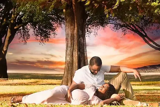 A loving couple shares a quiet moment beneath the trees during an outdoor maternity session in Killeen, TX. The soft sunset glow paints the sky in warm colors as they smile and connect over the joy of expecting.