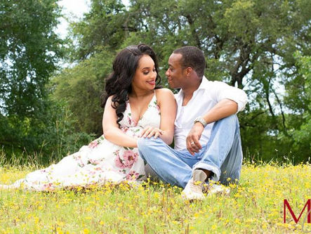 Pregnant couple sitting in a field of yellow wildflowers in Belton, TX, sharing an intimate moment