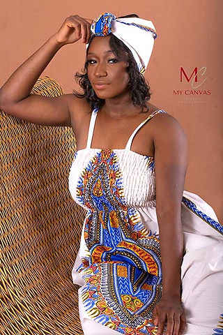 An African American woman posing confidently in a white sailor hat and a vibrant, patterned dress, exuding elegance and a sense of adventure.