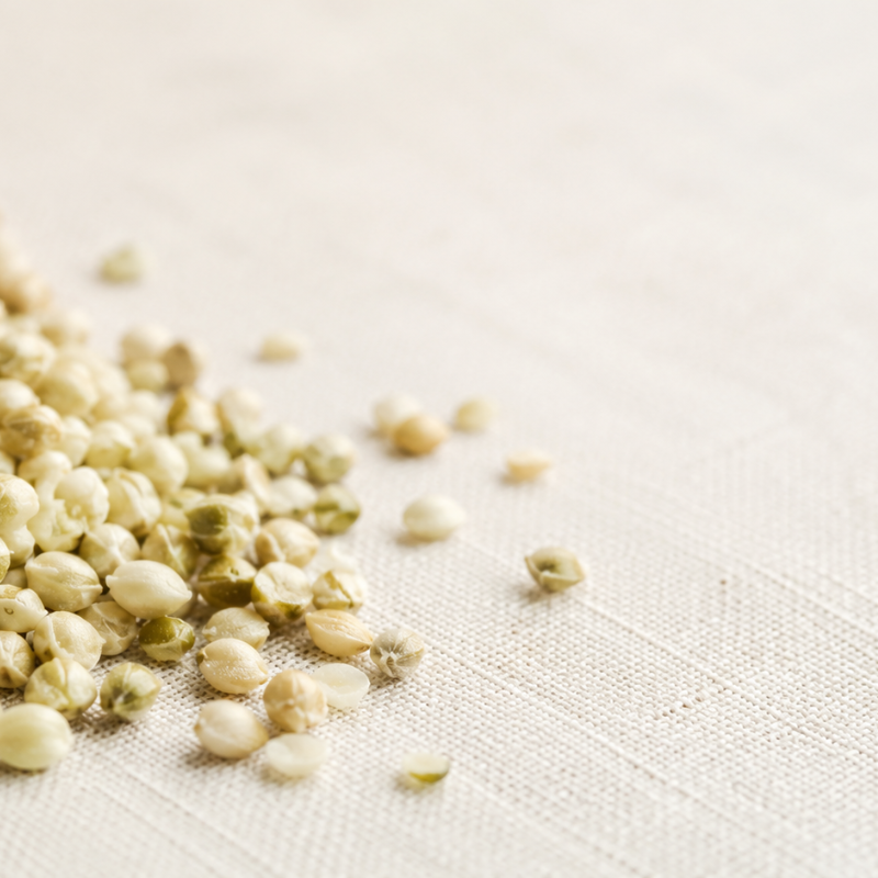 Raw hulled hemp seeds scattered on a pale linen surface