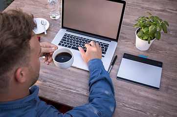 Mann sitzt am Laptop mit Kaffeetasse, auf dem Bildschirm ist ein Seelenstern – Online-Ausbildung zur Seelenplan-Lehrerin