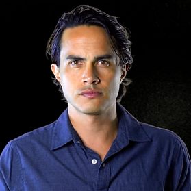 Jonathan Otto wearing a blue collared shirt against a dark background.
