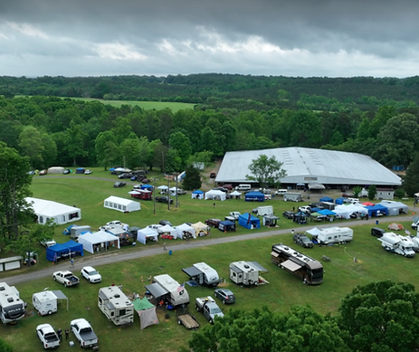 Aerial view of VanHoy Farms in Harmony, North Carolina, showing RVs, tents, vendor booths, and a large event barn surrounded by green fields and forested hills.