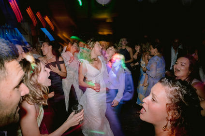 Braut und Bräutigam beim ersten Hochzeitstanz, Gäste im Hintergrund