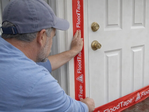 Homeowner applying flood insurance gap protection with FloodTape® to seal door against rising floodwater