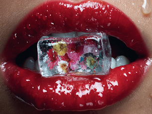 Künstlerische Nahaufnahme roter Lippen mit einem Eiswürfel als Symbol für impulsive Aufmerksamkeit und die flüchtige Wirkung einzelner Werbeanzeigen.