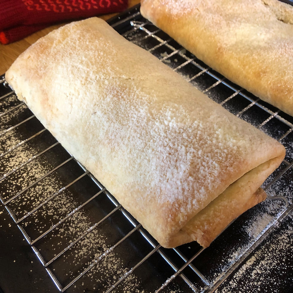 A baked strudel pastry, sprinkled with icing sugar.