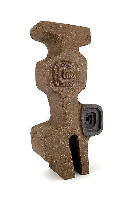 A textured, abstract brown sculpture casts intricate shadows on a wall