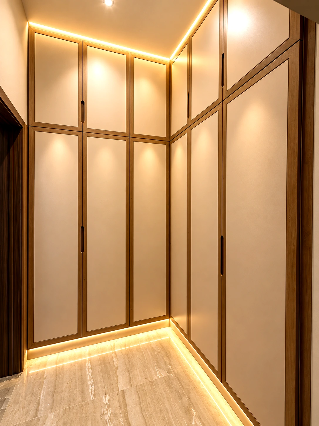 Full-height fitted wardrobe doors with timber frames and warm base lighting.