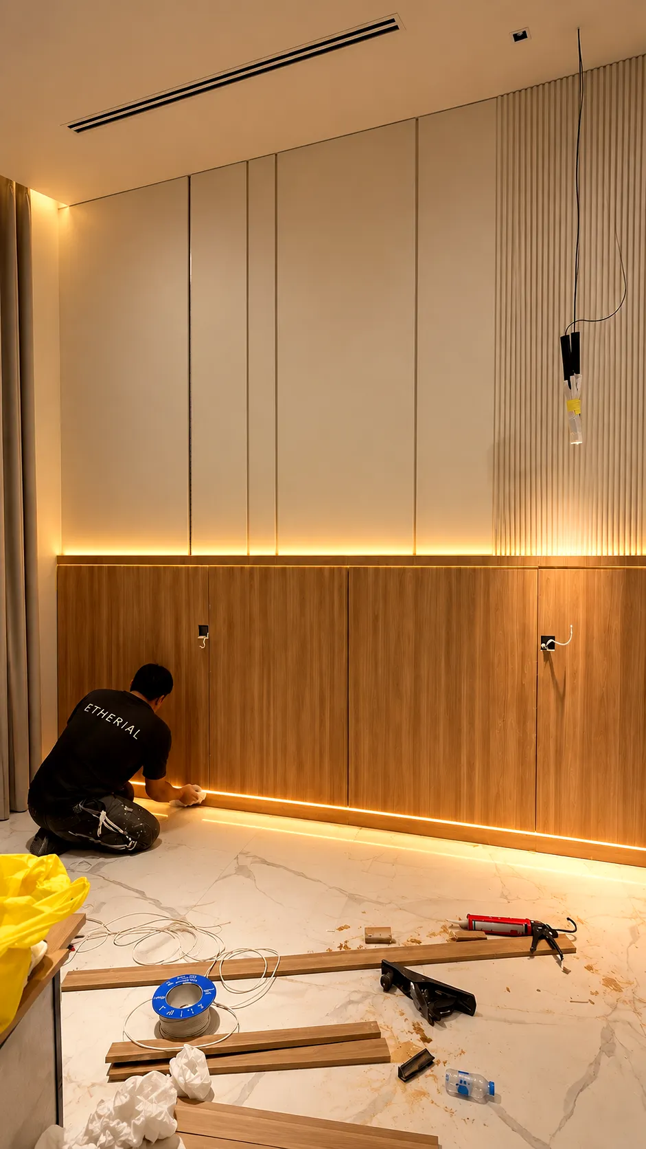 Installer fitting timber wall panels and bedroom joinery beneath integrated lighting.