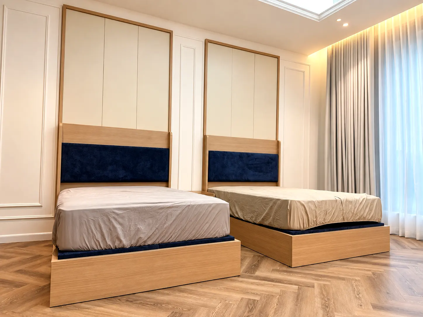 Custom twin beds with paneled headboard wall and integrated bedside lighting.