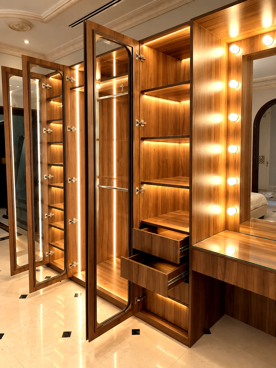 Glass-fronted dressing-room wardrobes with warm lighting and an integrated vanity area.