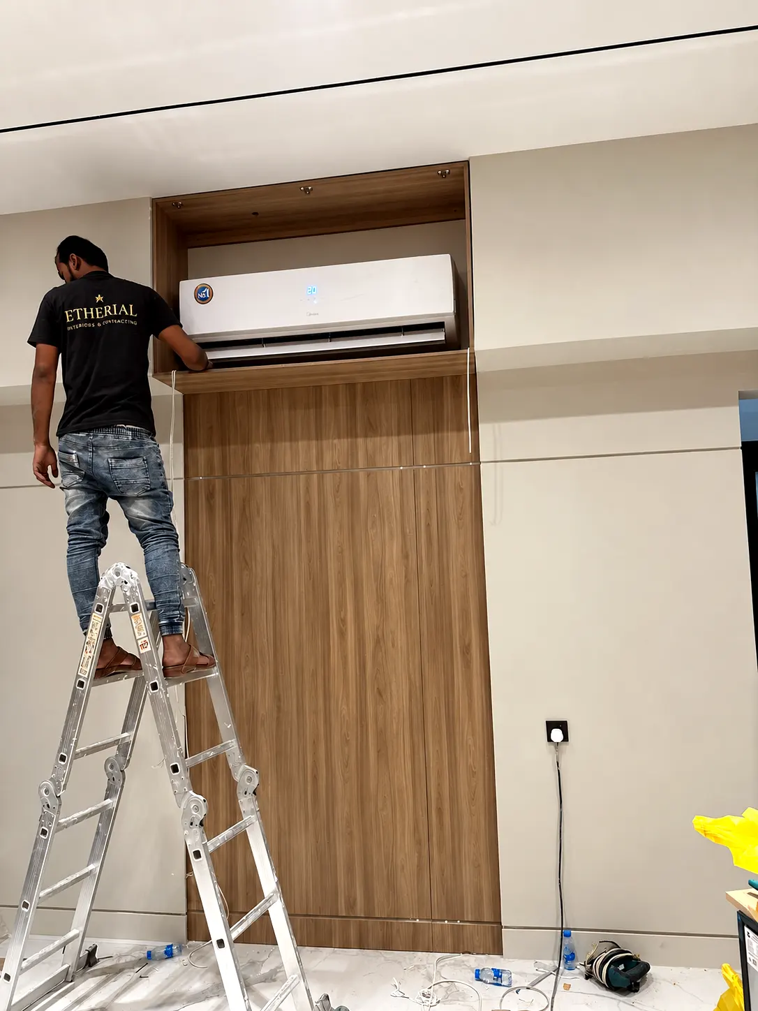 On-site fitting of timber wall cladding around a wall-mounted air-conditioning unit.
