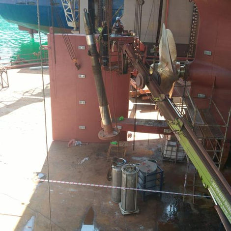 Geminin alt kısmı, kırmızı gövdesi ve bakım onarım çalışmaları yapan işçilerle birlikte görülüyor.