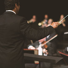 Conductor waving baton over orchestra