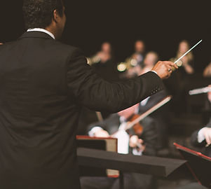Conductor waving baton over orchestra