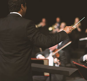 Conductor waving baton over orchestra