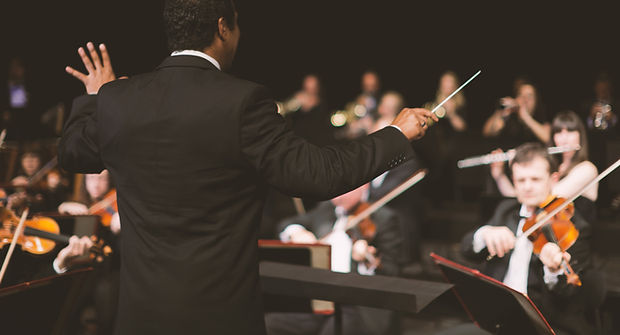 Conductor waving baton over orchestra