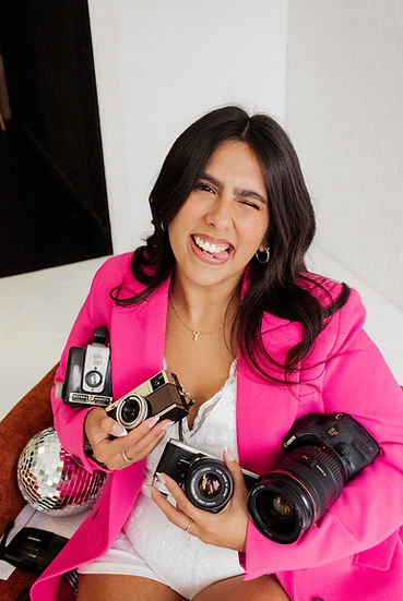 photographer in pink blazer holding cameras