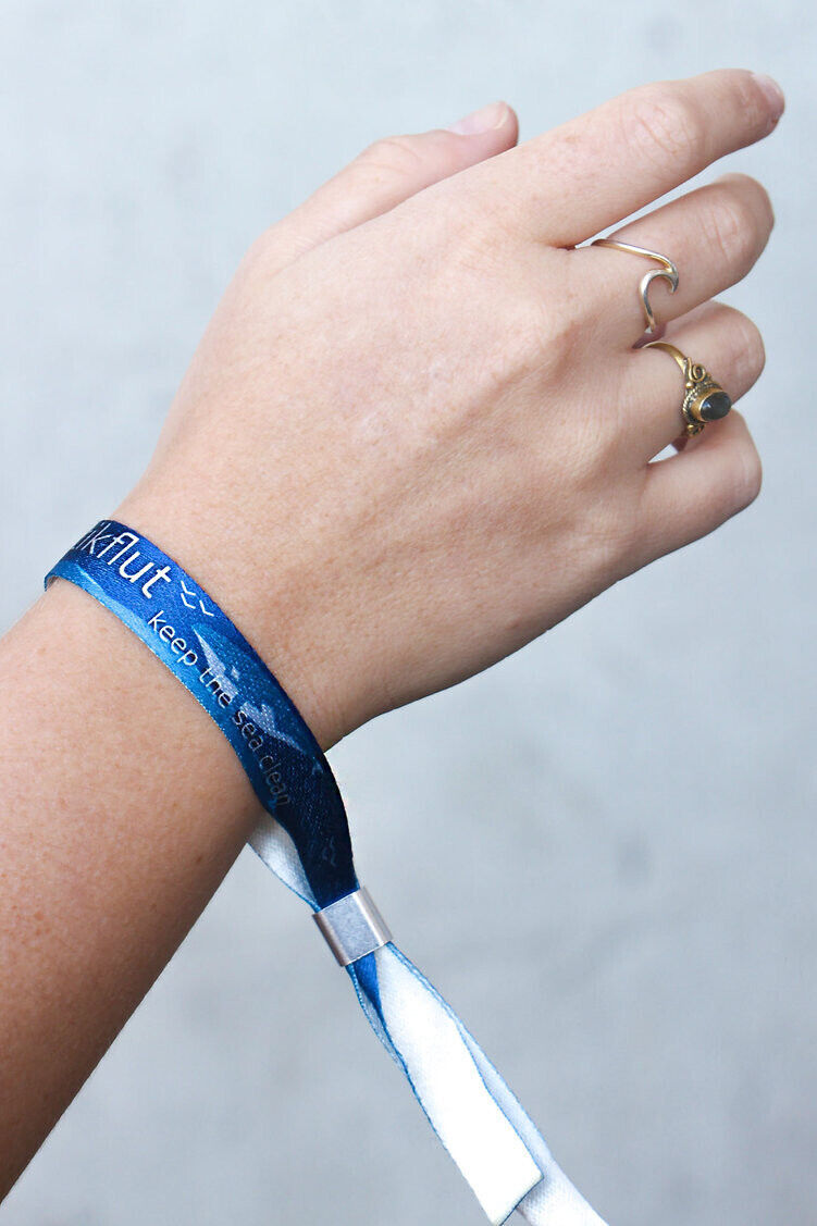 Miniature : Hand mit blauem Armband.