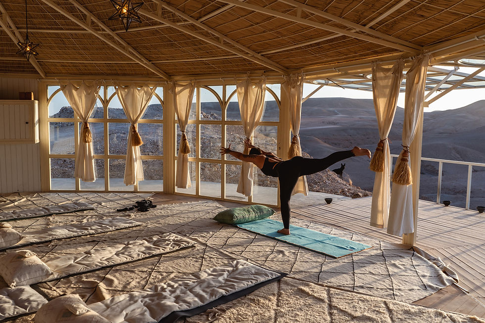 A solo yogi practices seated meditation as the sun rises over serene desert dunes, embodying a safe and tranquil retreat environment.