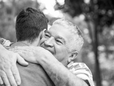 A senior man hugging adult son