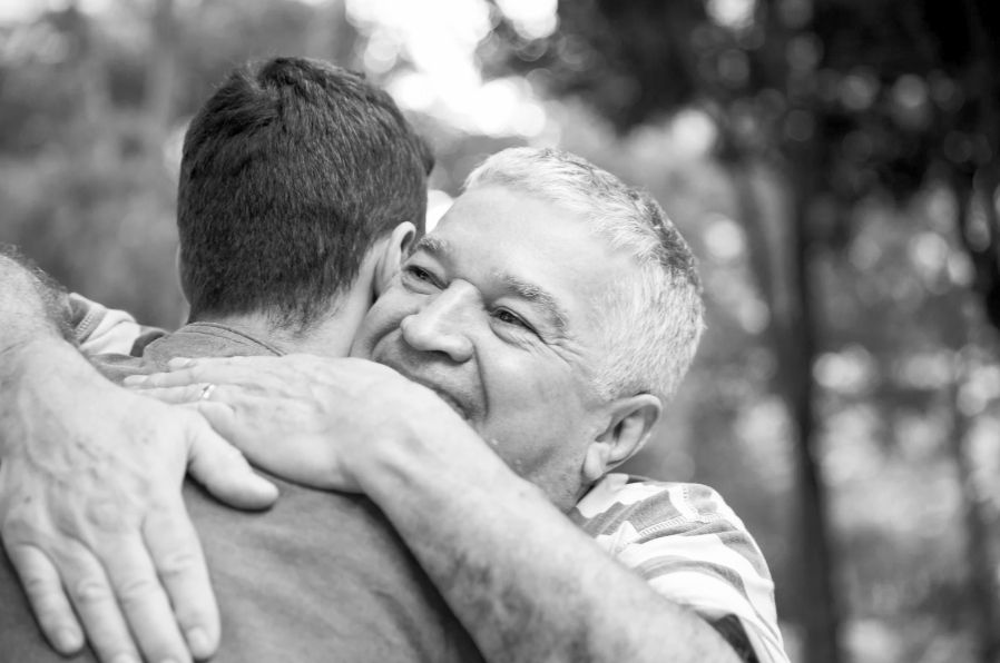 A senior man hugging adult son