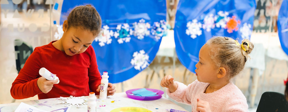 Two children create snowflakes in the Art Studio at the Cayton