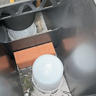 A bucket turned upside down in a large planter props up faux plants.