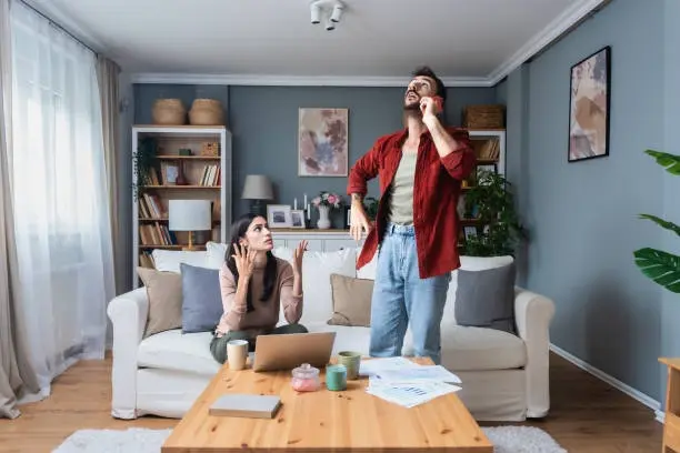 Frustrated couple hears upstairs noise in Queenstown apartment living room