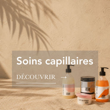 Catégorie Soins capillaires : des produits capillaires de la marque Cut By Fred posés sur du sable.